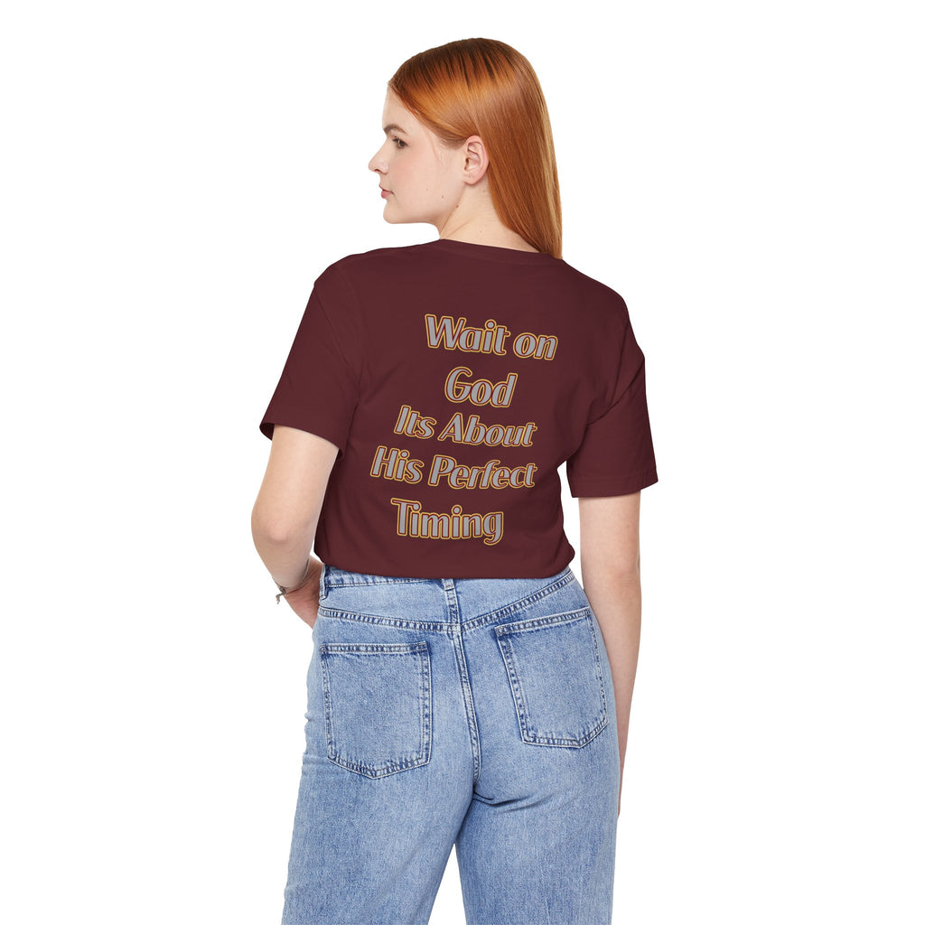 Person wearing a maroon t-shirt with text on the back, standing against a white background